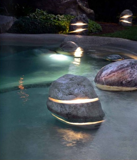 Diffusore a forma di roccia semi-immerso in piscina, con luce integrata